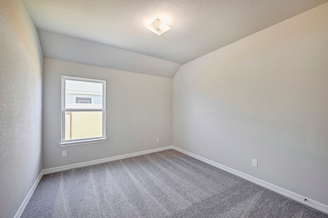 unfurnished room with carpet flooring, a textured ceiling, and lofted ceiling