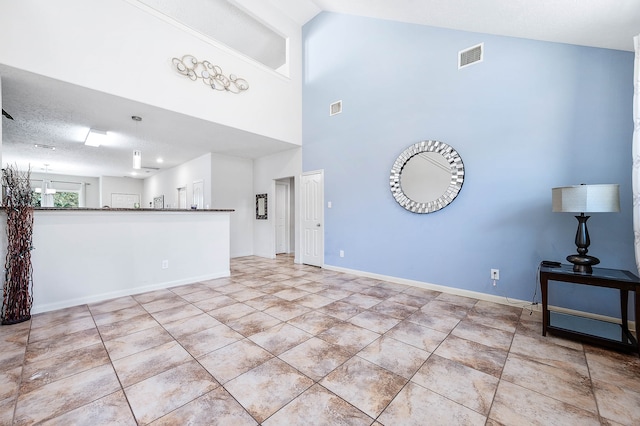 unfurnished living room featuring a high ceiling, a textured ceiling, and light tile patterned floors