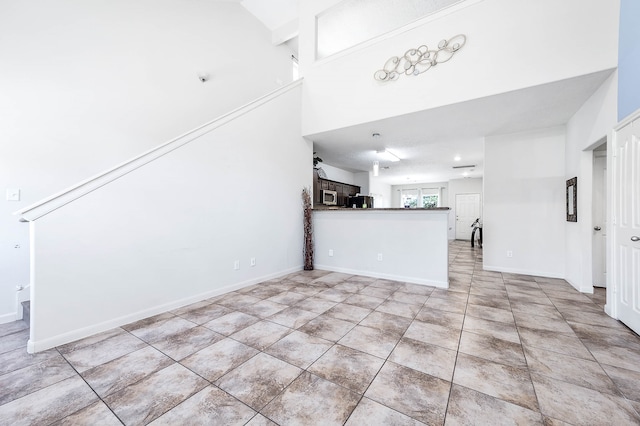 unfurnished living room featuring light tile patterned flooring and a towering ceiling