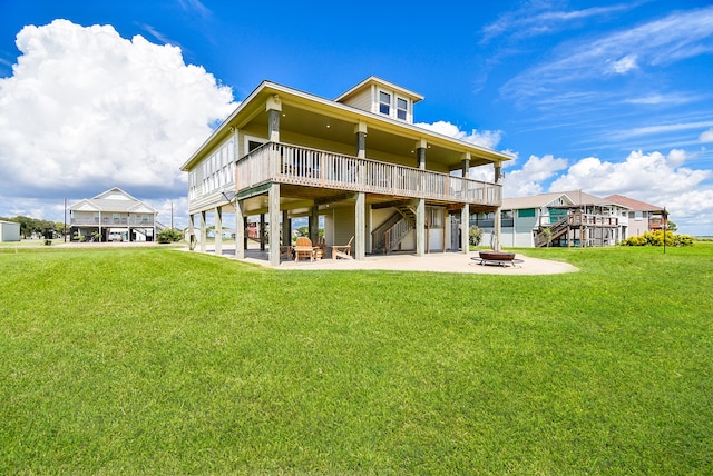 back of property featuring a fire pit, a patio area, a yard, and a wooden deck