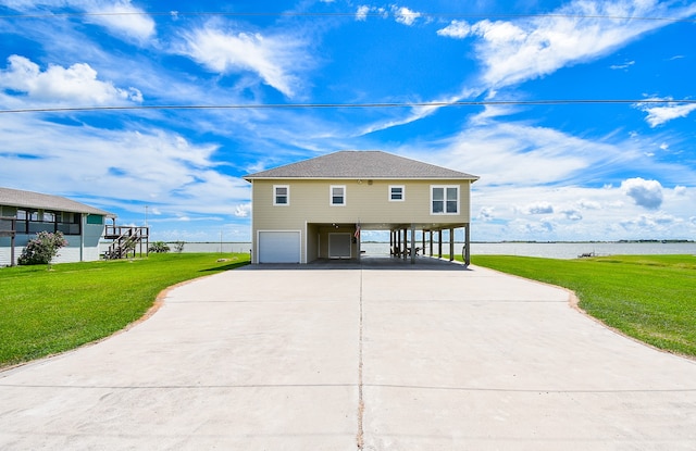 exterior space featuring a water view, a garage, a carport, and a lawn