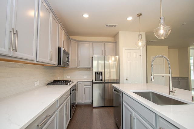 kitchen with light stone countertops, appliances with stainless steel finishes, gray cabinetry, sink, and dark hardwood / wood-style floors