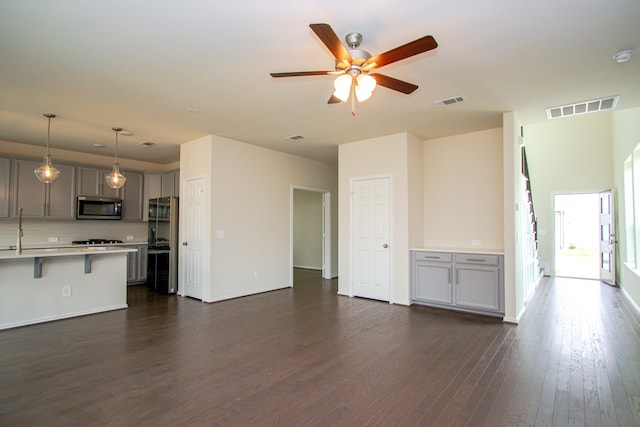 unfurnished living room with ceiling fan, dark hardwood / wood-style flooring, and sink