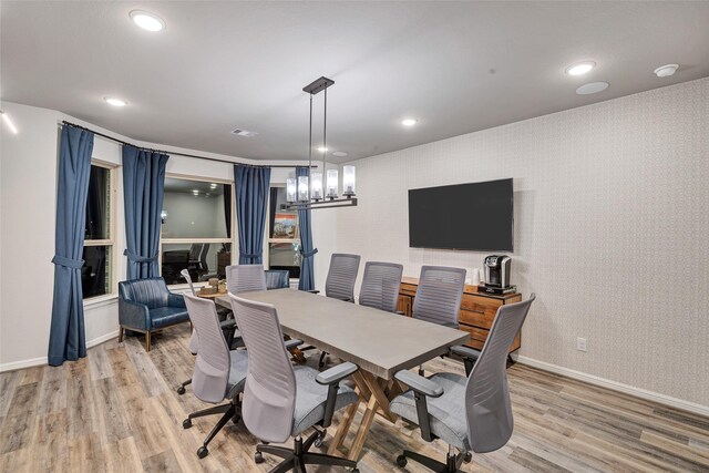 dining area with light hardwood / wood-style flooring and a notable chandelier