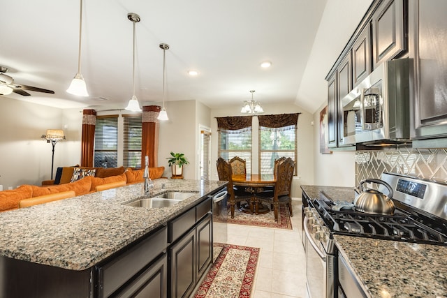 kitchen with stainless steel appliances, sink, light tile patterned floors, a center island with sink, and lofted ceiling