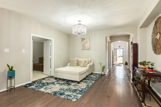 sitting room featuring dark wood-type flooring and an inviting chandelier