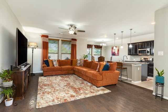 living room featuring ceiling fan with notable chandelier, dark hardwood / wood-style flooring, and sink