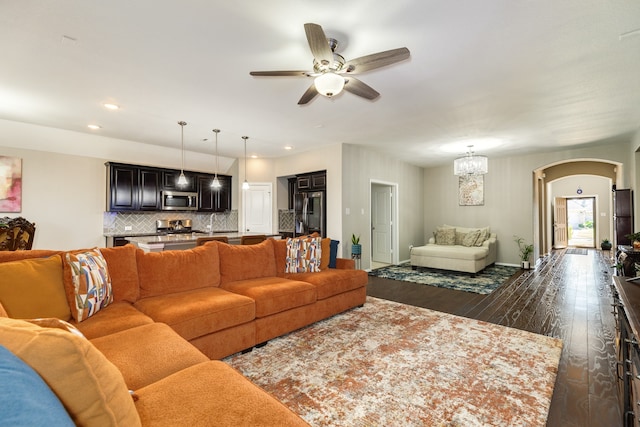 living room featuring ceiling fan with notable chandelier and dark hardwood / wood-style flooring