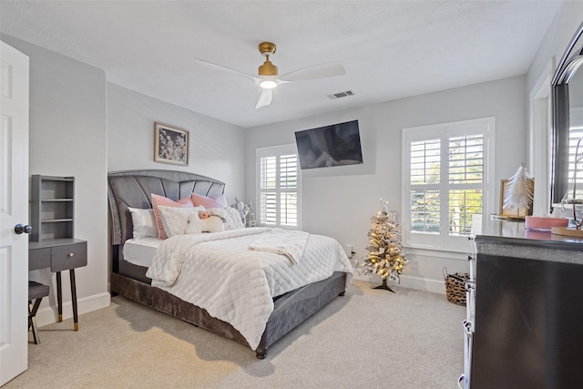 bedroom featuring multiple windows, ceiling fan, and light colored carpet