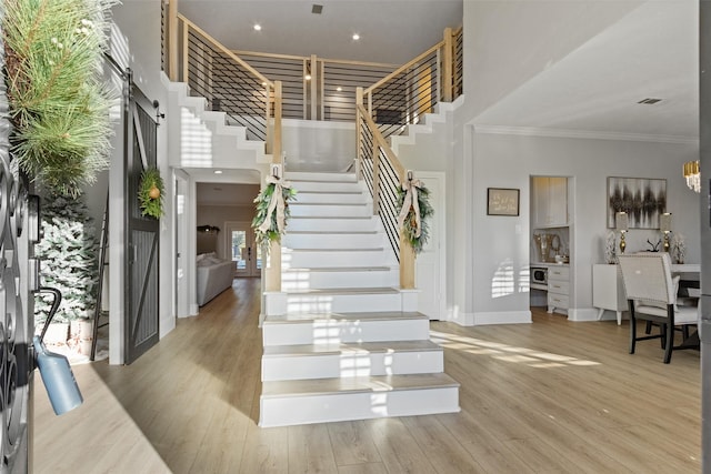 foyer entrance featuring a high ceiling, light hardwood / wood-style floors, and ornamental molding