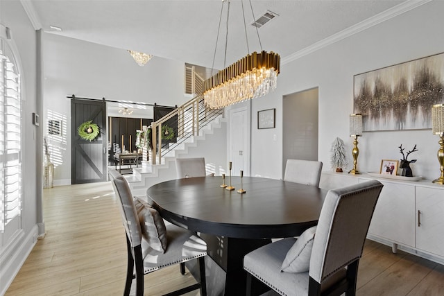 dining area featuring a barn door, ornamental molding, a notable chandelier, and hardwood / wood-style flooring