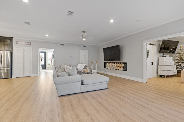 living room with light hardwood / wood-style flooring, ceiling fan, and ornamental molding