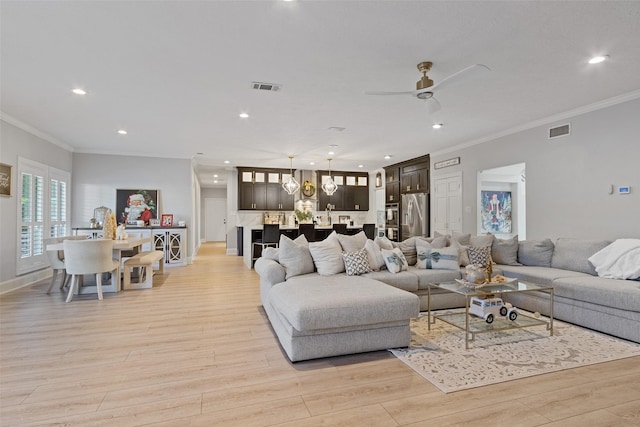 living room with light hardwood / wood-style flooring, ceiling fan, and crown molding