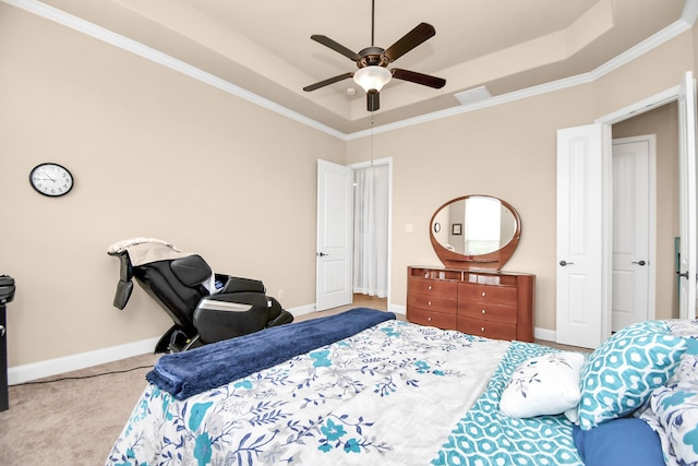 carpeted bedroom with a tray ceiling, ceiling fan, and ornamental molding