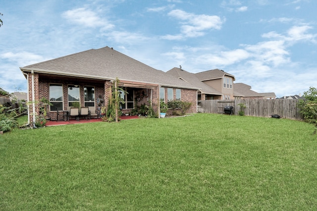 back of property with a patio area and a lawn