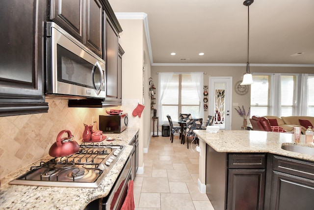 kitchen featuring dark brown cabinetry, stainless steel appliances, decorative light fixtures, and ornamental molding