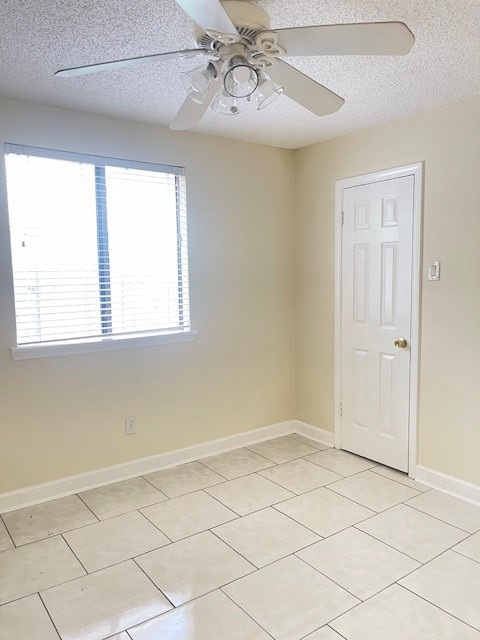 tiled spare room with a textured ceiling and ceiling fan