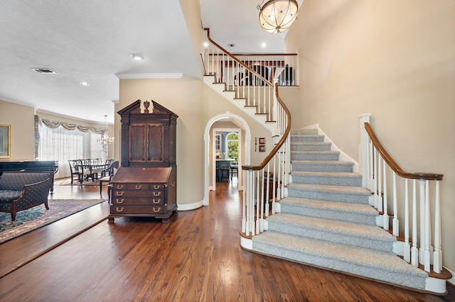 stairway featuring hardwood / wood-style floors, ornamental molding, a wealth of natural light, and a notable chandelier