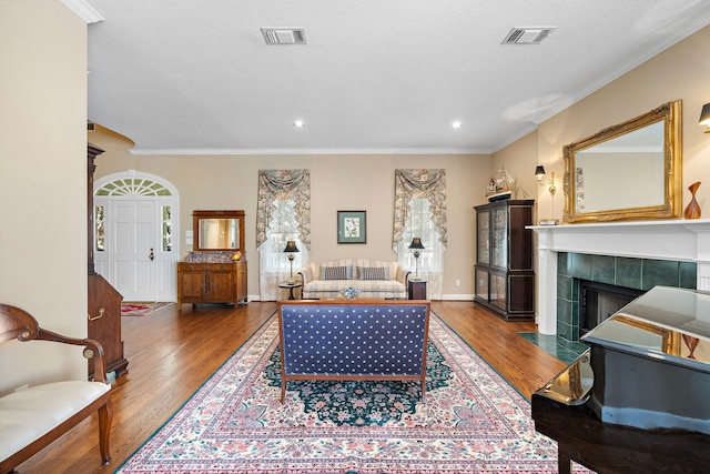 living room featuring a fireplace, hardwood / wood-style floors, a textured ceiling, and ornamental molding