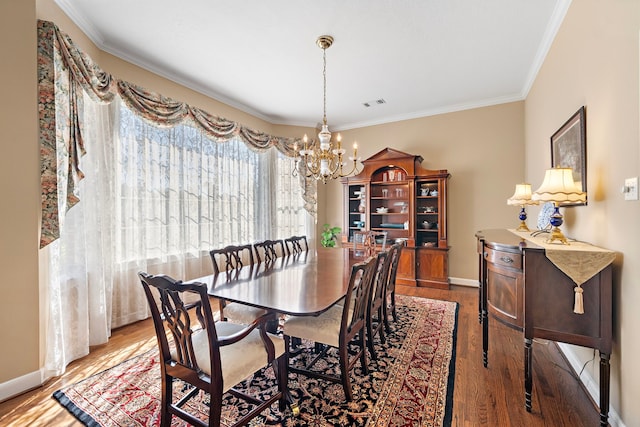 dining space featuring hardwood / wood-style floors, an inviting chandelier, and ornamental molding