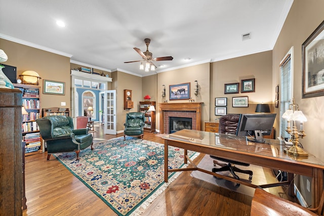 office area with hardwood / wood-style floors, french doors, a brick fireplace, ceiling fan, and ornamental molding