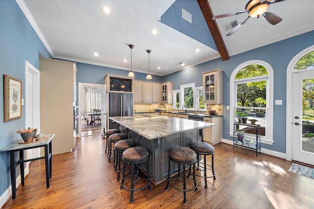 kitchen with light stone countertops, dark hardwood / wood-style flooring, backsplash, decorative light fixtures, and a kitchen island