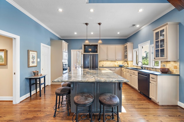 kitchen featuring a center island, black dishwasher, light hardwood / wood-style flooring, dark stone counters, and decorative light fixtures