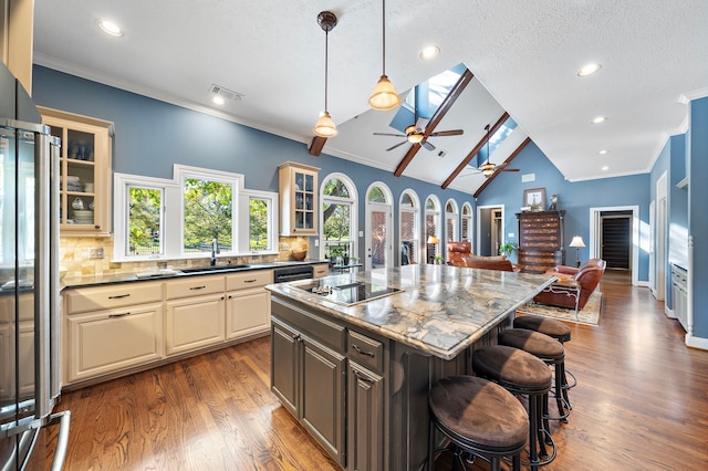 kitchen featuring lofted ceiling, black appliances, sink, a kitchen island, and a kitchen bar