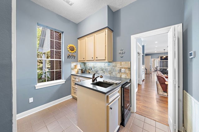 kitchen featuring backsplash, sink, wine cooler, a textured ceiling, and light hardwood / wood-style floors