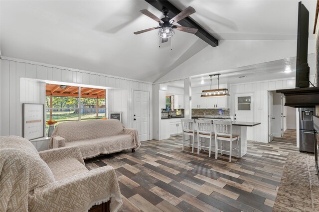 living room with lofted ceiling with beams, ceiling fan, and dark wood-type flooring