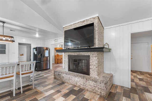 living room with vaulted ceiling, wood walls, a large fireplace, and dark hardwood / wood-style floors