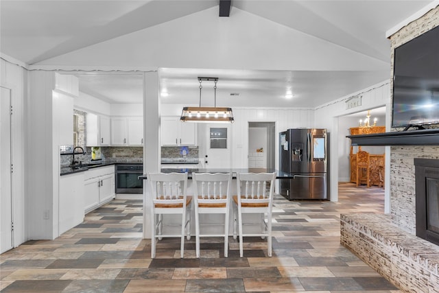 kitchen with decorative backsplash, appliances with stainless steel finishes, vaulted ceiling with beams, white cabinetry, and hanging light fixtures