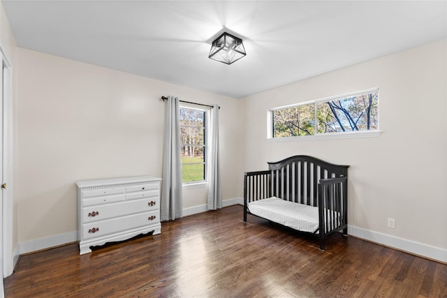 bedroom with a nursery area and dark hardwood / wood-style floors