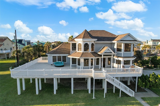 back of property with a shingled roof, a residential view, a lawn, and a deck