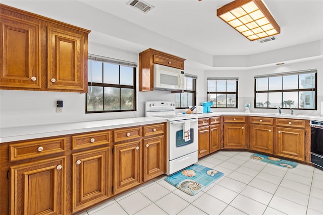 kitchen with light countertops, white appliances, visible vents, and brown cabinets