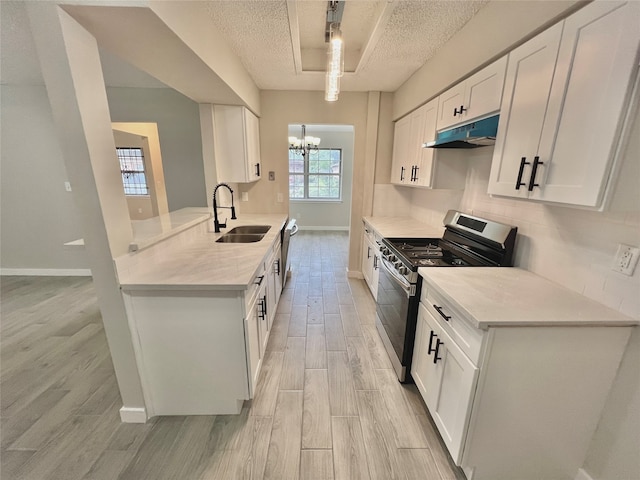 kitchen featuring white cabinets, sink, a textured ceiling, a notable chandelier, and gas stove