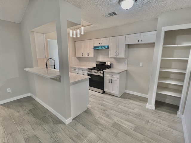 kitchen featuring kitchen peninsula, light hardwood / wood-style floors, white cabinetry, and stainless steel gas range oven