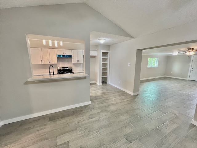 kitchen featuring kitchen peninsula, stainless steel range, a textured ceiling, ceiling fan, and white cabinetry