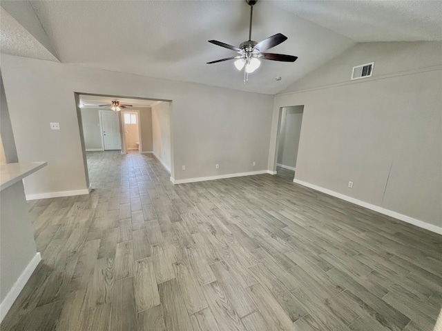 unfurnished living room with a textured ceiling, light hardwood / wood-style floors, vaulted ceiling, and ceiling fan