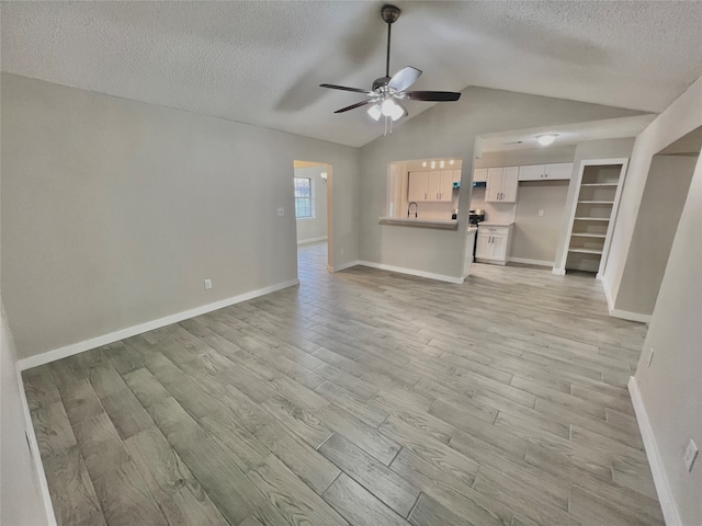 unfurnished living room featuring a textured ceiling, light wood-type flooring, vaulted ceiling, and ceiling fan