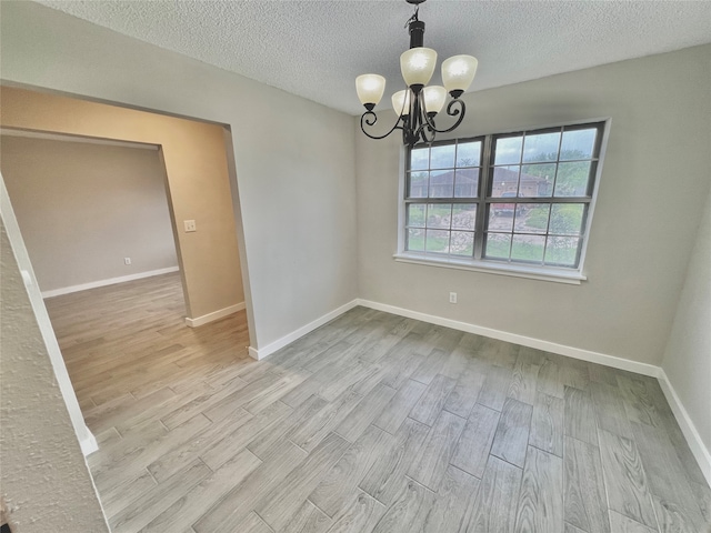 unfurnished dining area with light hardwood / wood-style flooring, a textured ceiling, and an inviting chandelier