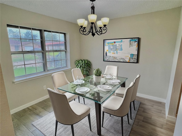 dining area featuring wood-type flooring, a textured ceiling, and a chandelier