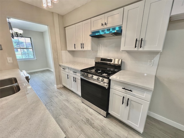 kitchen featuring light stone countertops, an inviting chandelier, stainless steel stove, and white cabinetry