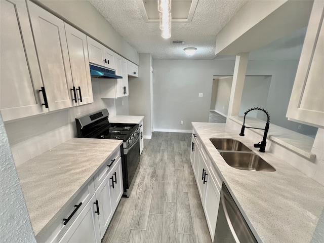 kitchen with appliances with stainless steel finishes, a textured ceiling, sink, light hardwood / wood-style flooring, and white cabinets