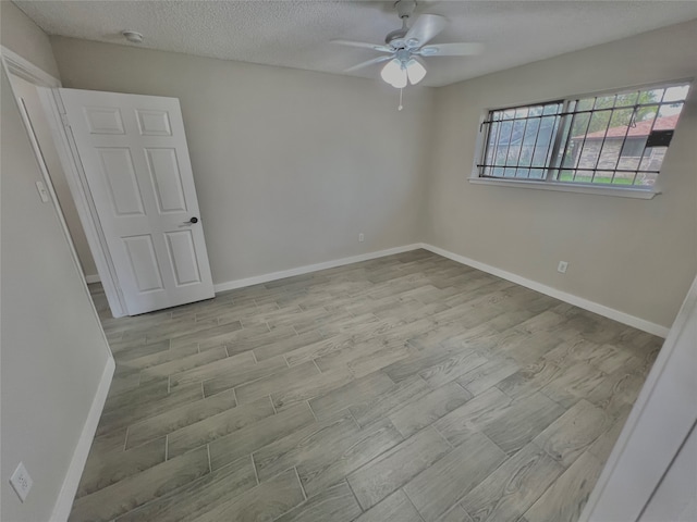 unfurnished room featuring a textured ceiling, light wood-type flooring, and ceiling fan