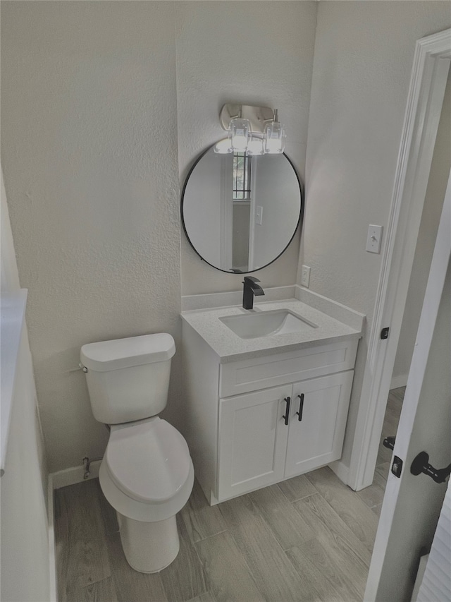 bathroom with vanity, wood-type flooring, and toilet