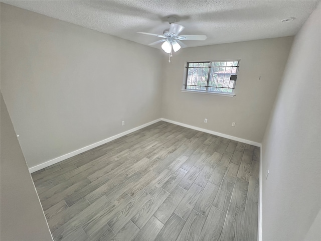 spare room with ceiling fan, light wood-type flooring, and a textured ceiling