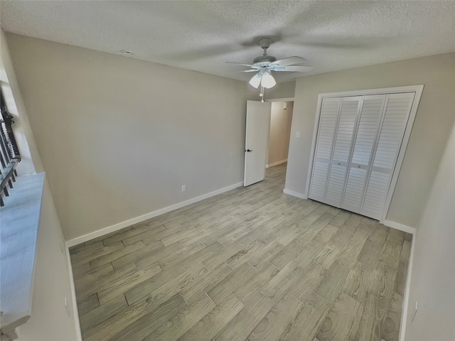 unfurnished bedroom featuring a closet, ceiling fan, light hardwood / wood-style flooring, and a textured ceiling