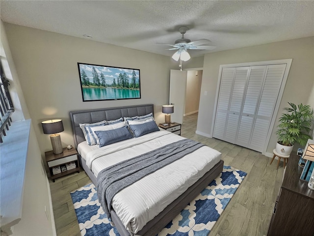 bedroom with a textured ceiling, a closet, light hardwood / wood-style flooring, and ceiling fan