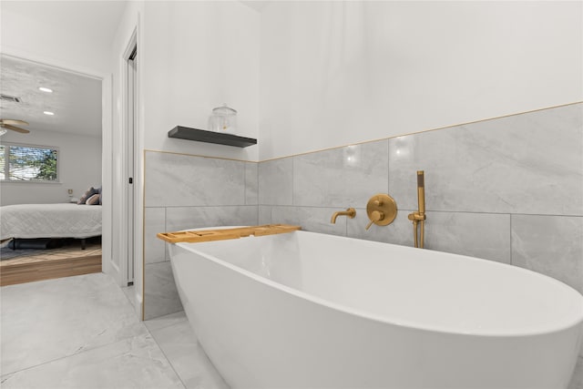 bathroom featuring a washtub, ceiling fan, and tile walls